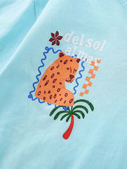Close-up of the cartoon leopard and palm tree chest graphic on a mint blue T-shirt