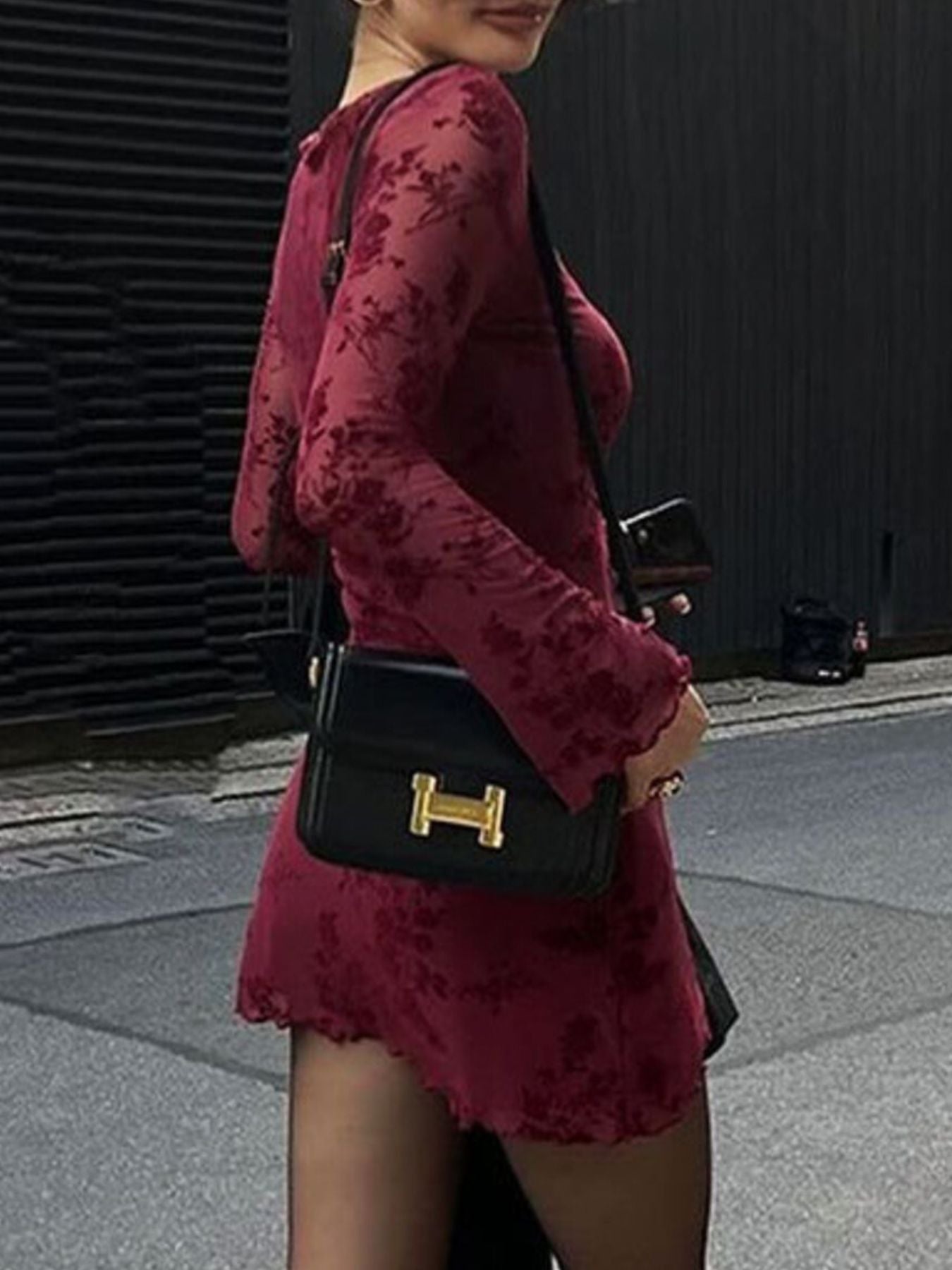 Burgundy floral long sleeve bodycon mini dress, side view outdoors carrying shoulder bag