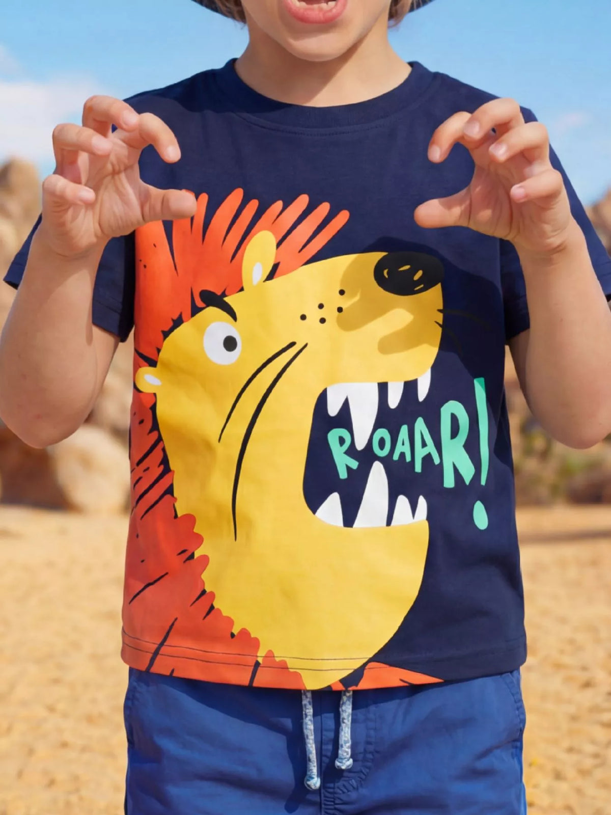 Dark blue children's short sleeve T-shirt shown worn outdoors with a large roaring yellow lion graphic