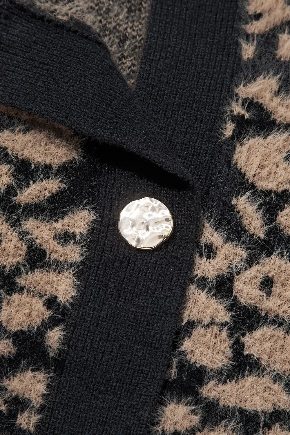 Close up of gold button on black placket of leopard print knit vest.