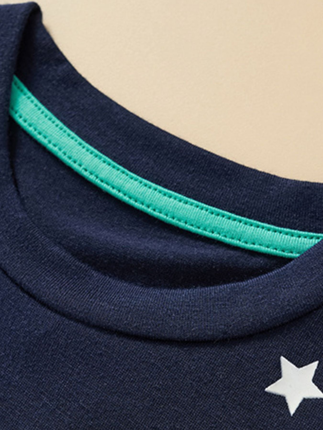 Close-up of the crew neckline with green inner trim on the children's dark navy t-shirt