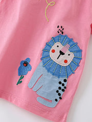 Angled close-up of the blue-maned lion and blue flower embroidery on pink fabric