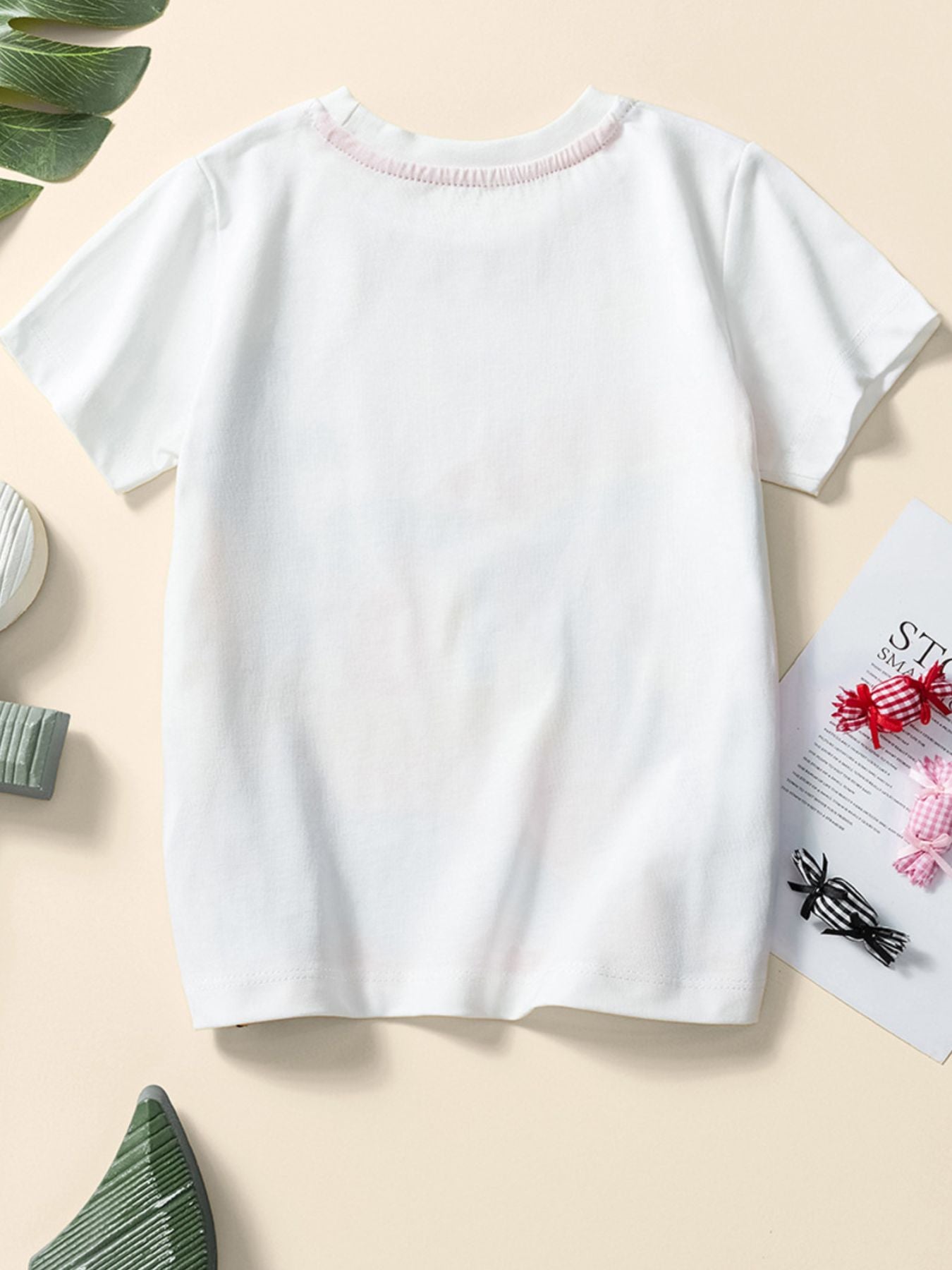 Back view of a children's plain white short sleeve tee with a coral trimmed round neckline