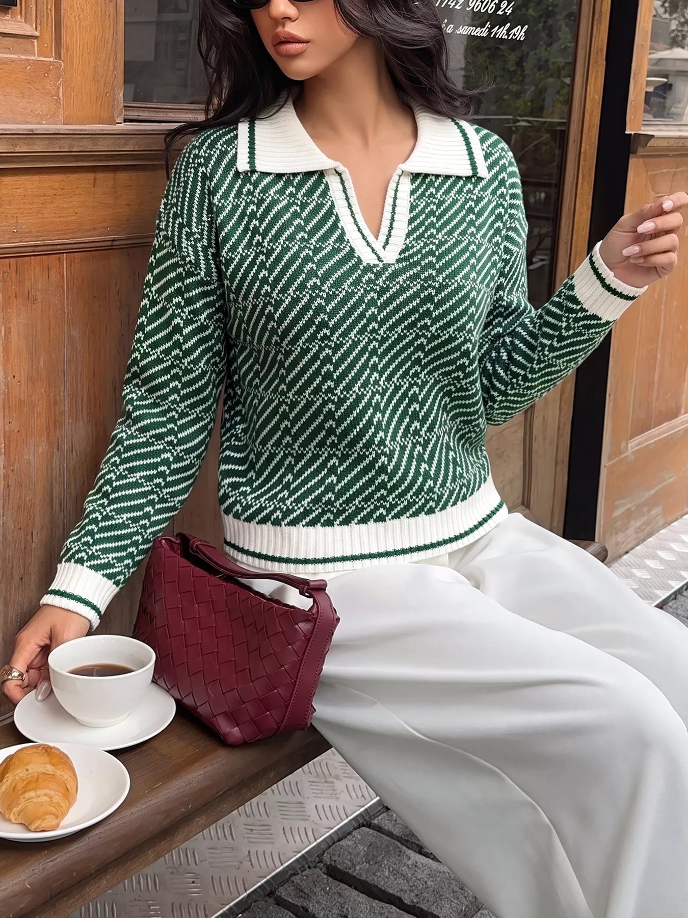 Seated on-model front view of the green geometric sweater with a white ribbed collar