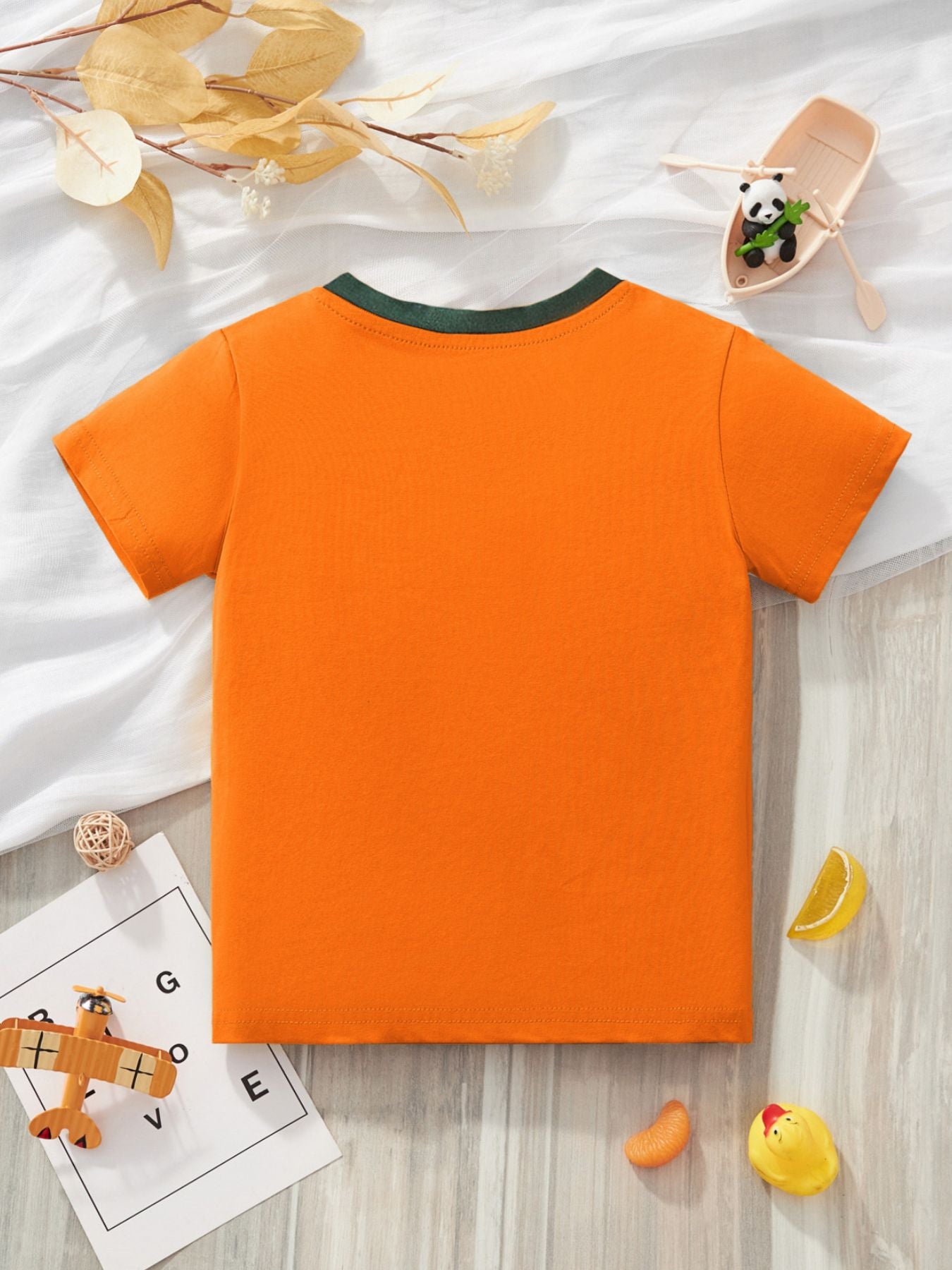 Back view of the plain orange children's T-shirt with green trim at the crew neckline