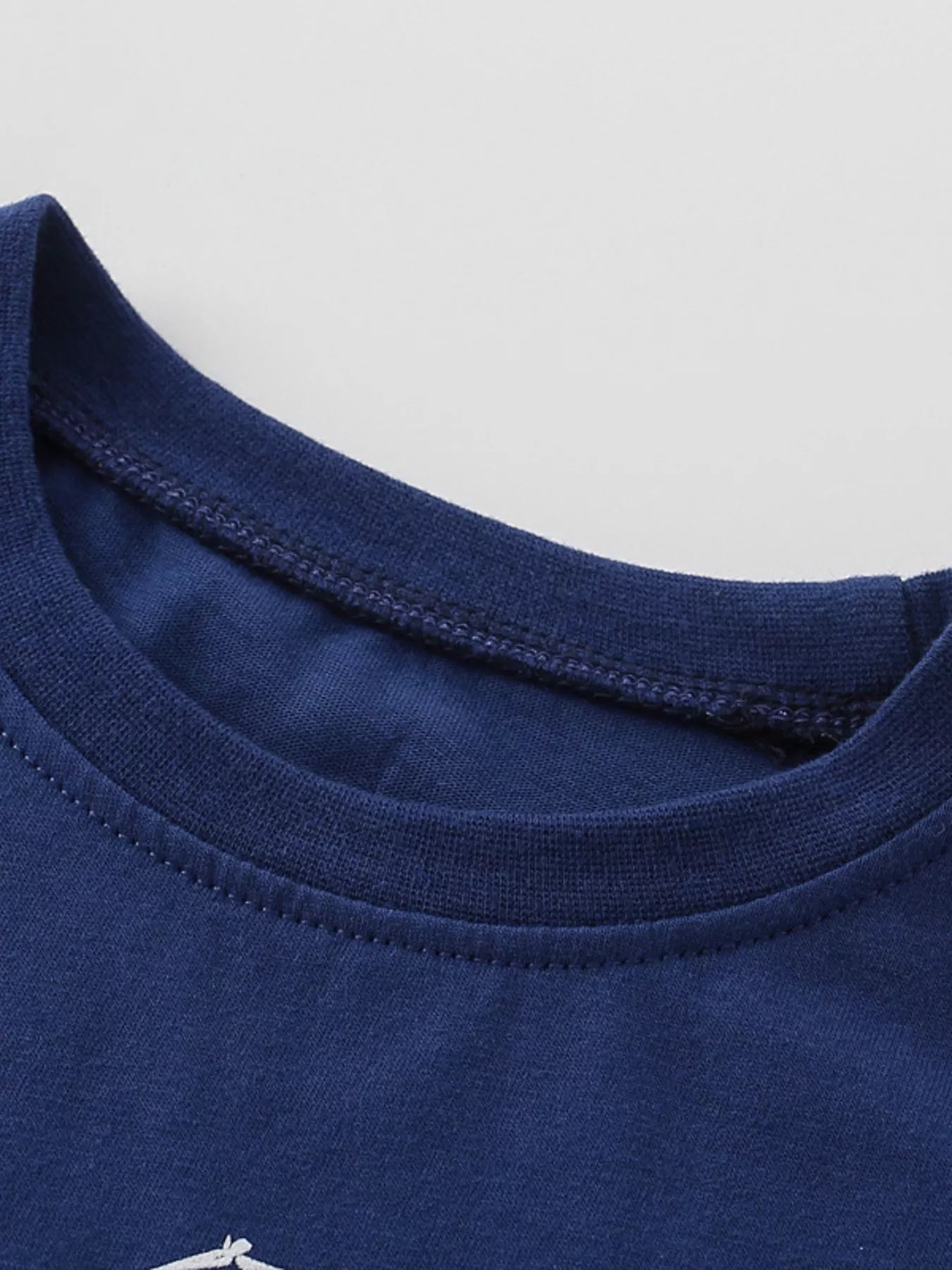 Close-up of ribbed crew neckline and stitching on navy children's tee
