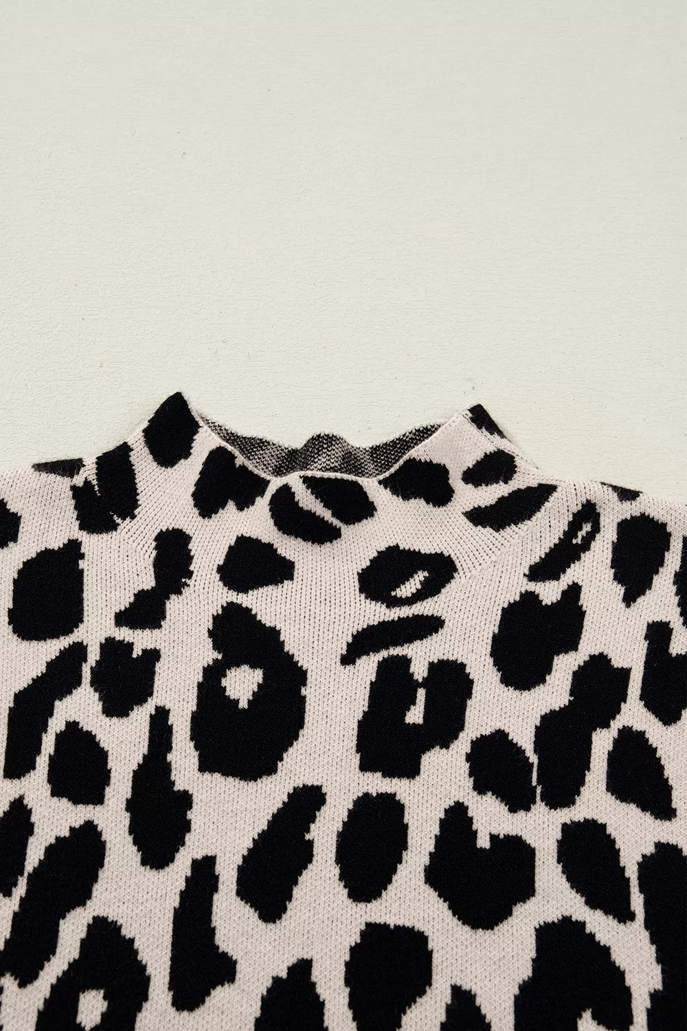 Close up detail of the high neckline on the black and cream leopard print knit sweater.