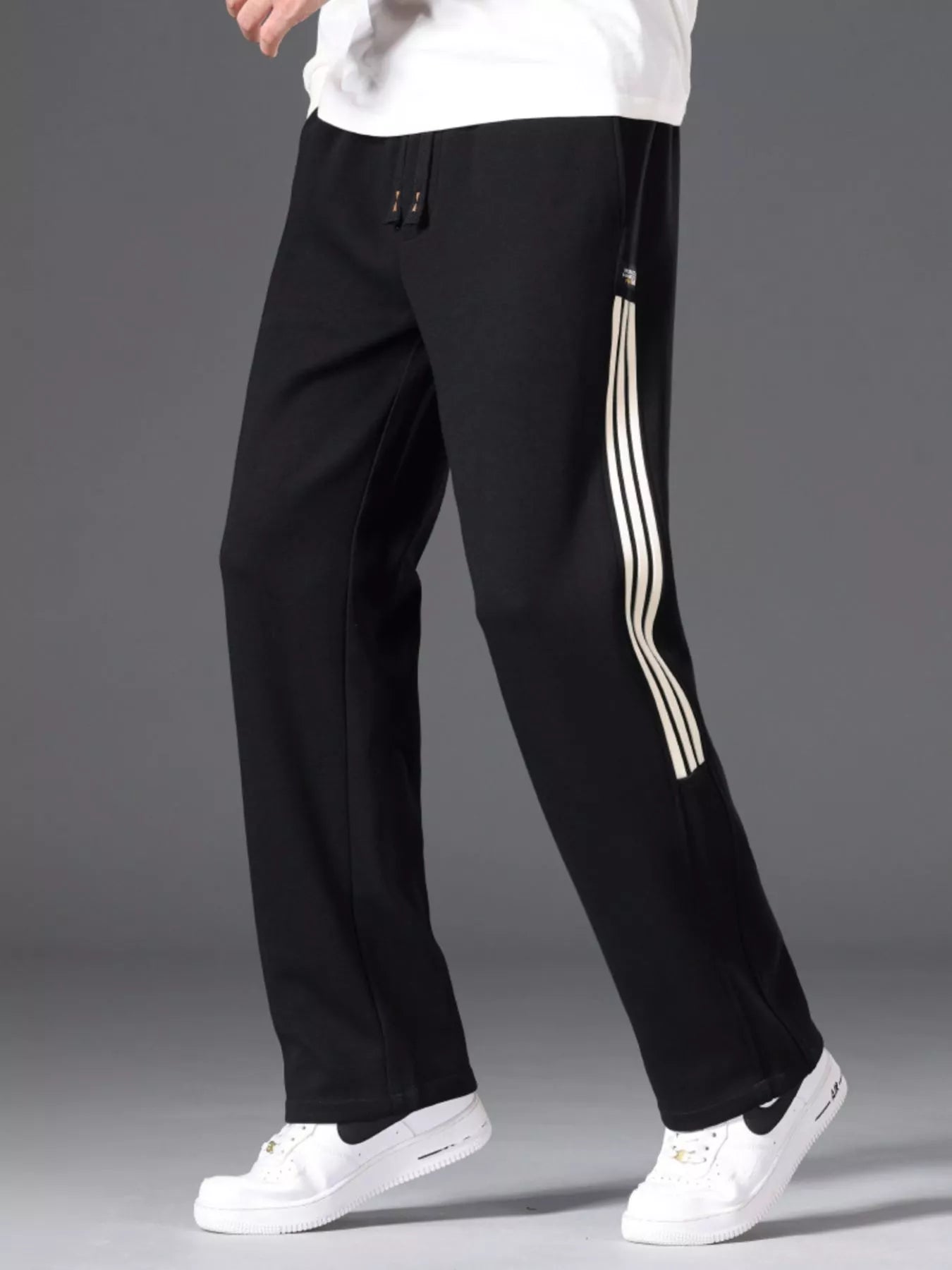 Men's black striped wide-leg pants with a drawstring waist and pockets.