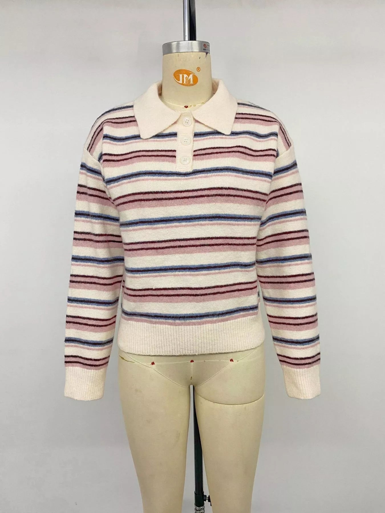 Front view of a cream striped polo sweater with a button placket on a mannequin