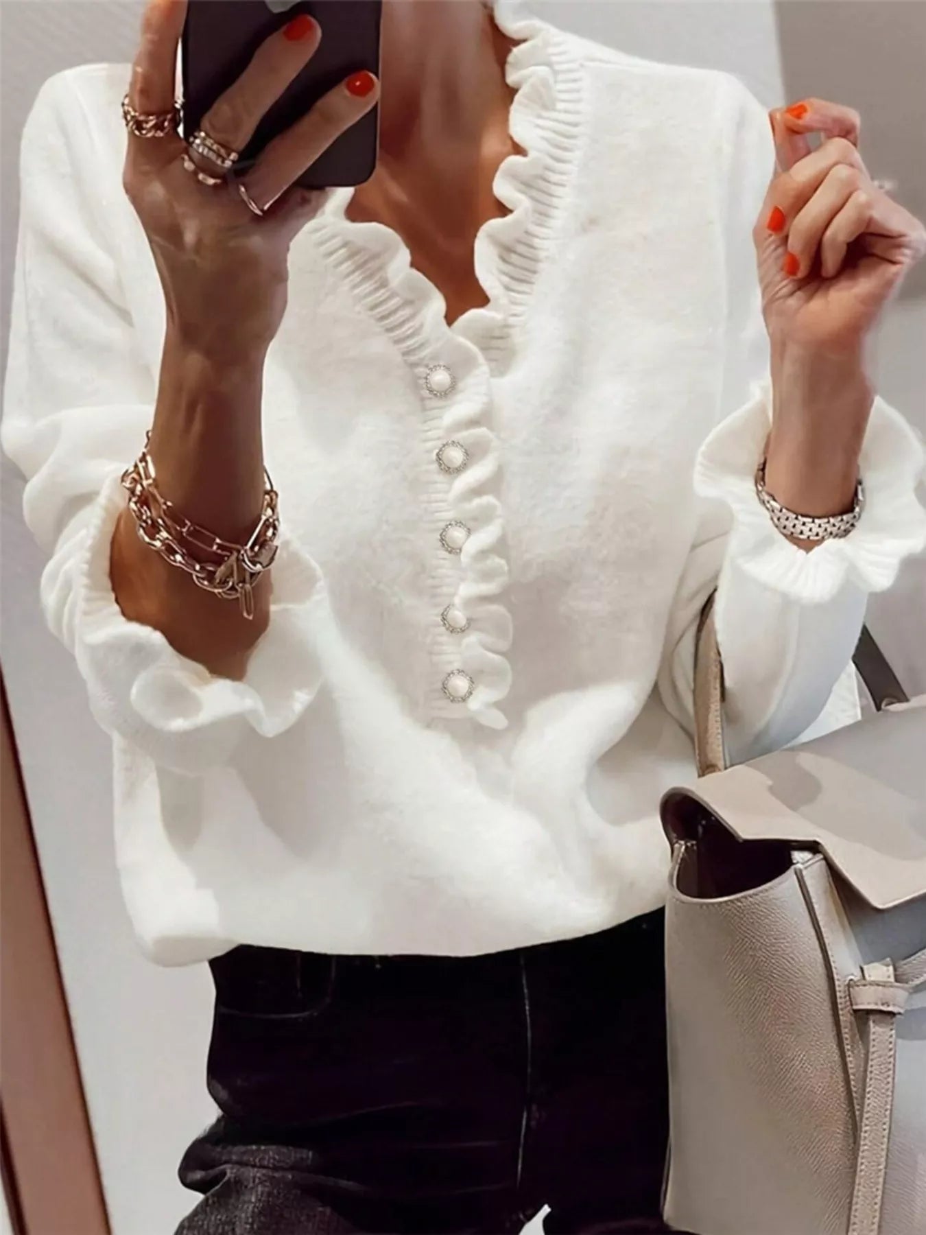 Mirror front view of a white ruffled sweater with pearl buttons and ruffled cuffs