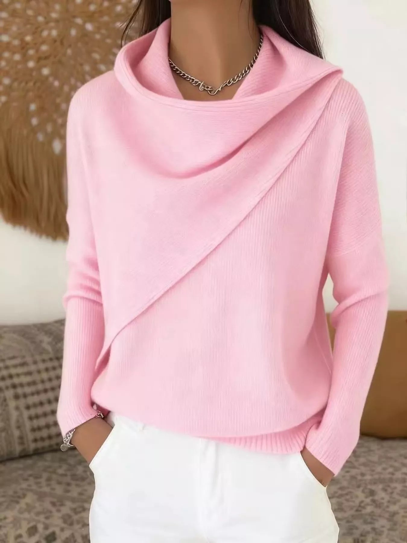 On-model front view of a pink cowl neck sweater with a draped asymmetric collar and long sleeves