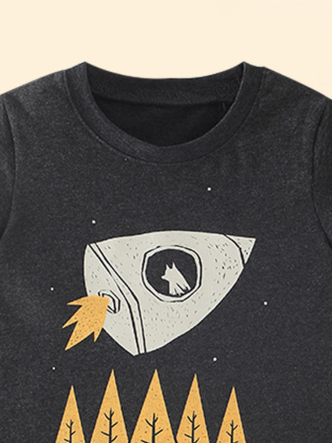 Close-up upper front of black children's t-shirt showing neckline and white rocket graphic