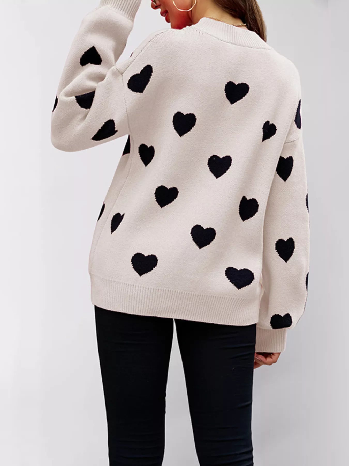 Back view of the cream dropped shoulder sweater with black hearts and ribbed hem.