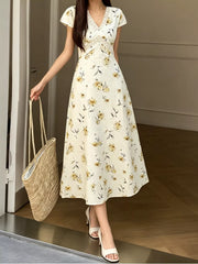 Full length front view of a yellow floral midi dress with lace trimmed V neck on a model