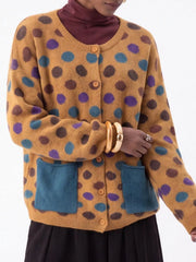 Close front view of mustard polka dot cardigan with buttons and teal pockets
