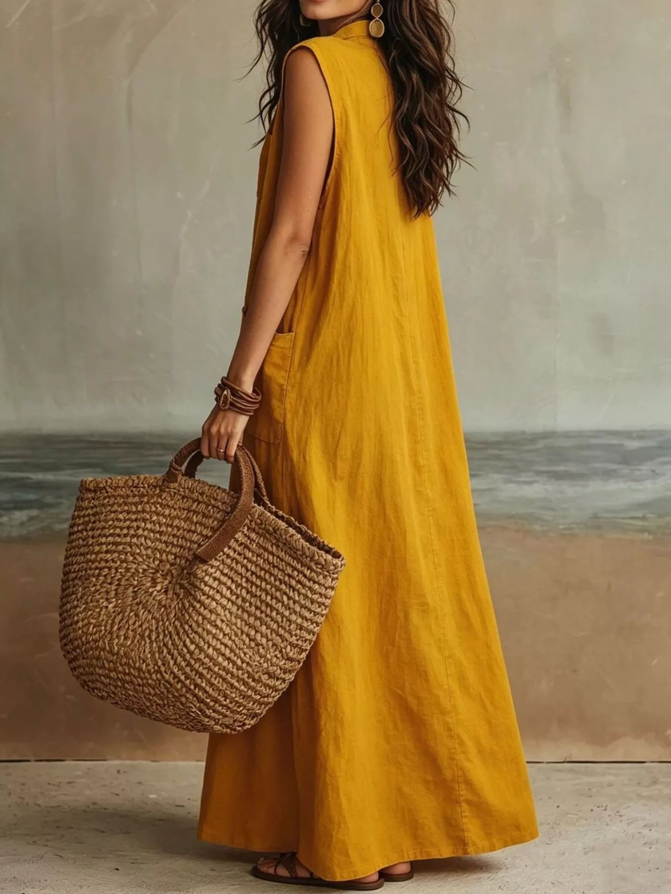 Back view of gold sleeveless button down linen maxi dress with woven tote bag
