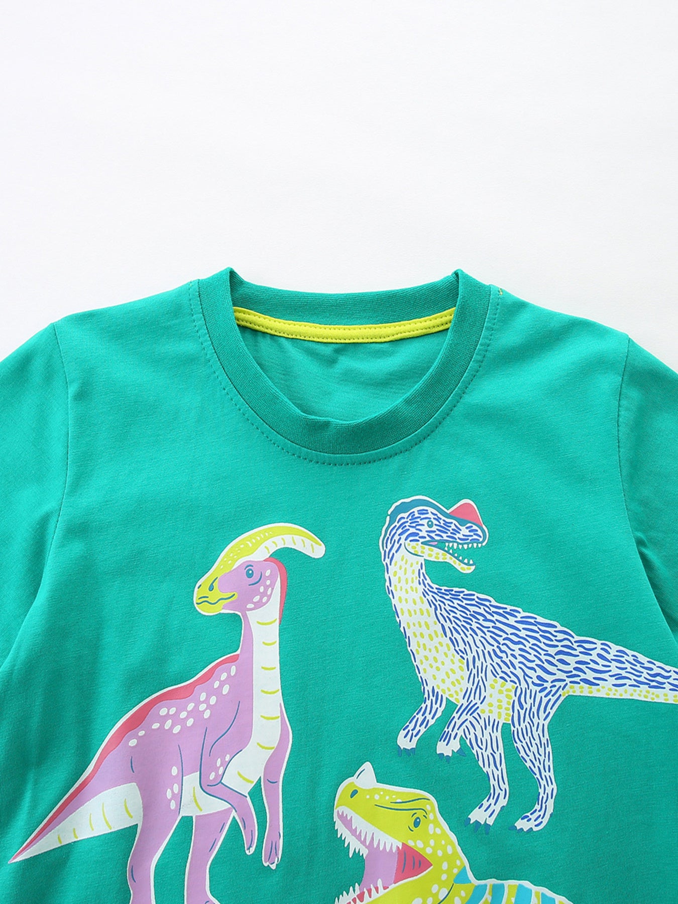 Close-up of turquoise crew neckline with yellow trim and the tops of colorful dinosaur prints