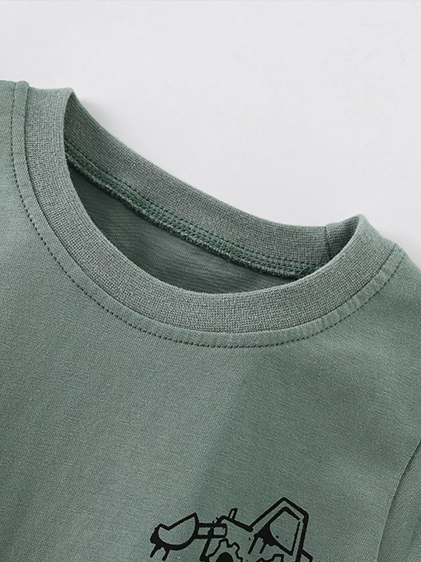 Close-up of the sage children's shirt neckline showing ribbed trim and neat stitching