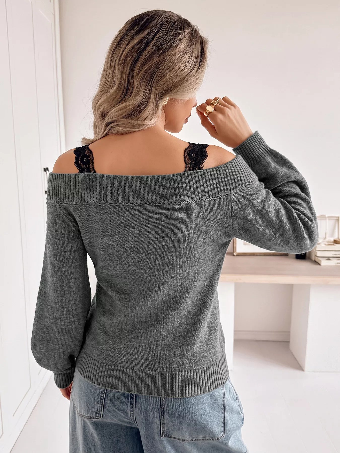 Back view of dark grey off shoulder lace trim sweater with light jeans