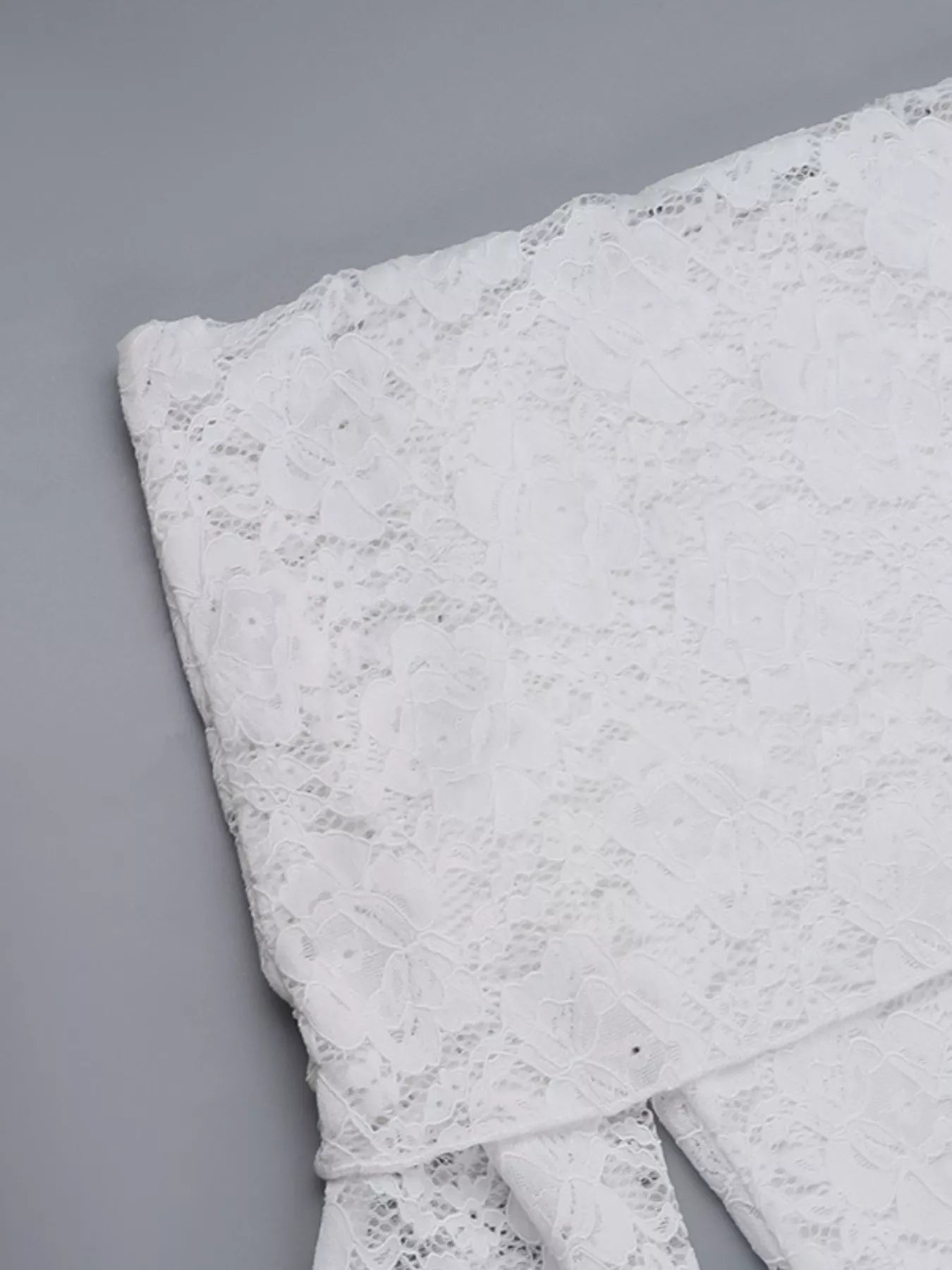Flat detail view of a white lace maxi dress bodice showing the floral lace texture