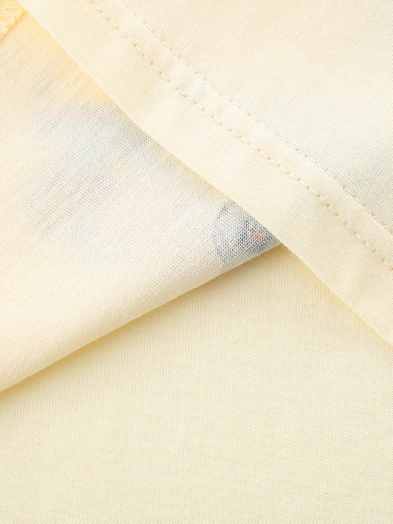 Close-up of the cream fabric and double stitching at the hem of the children's tee