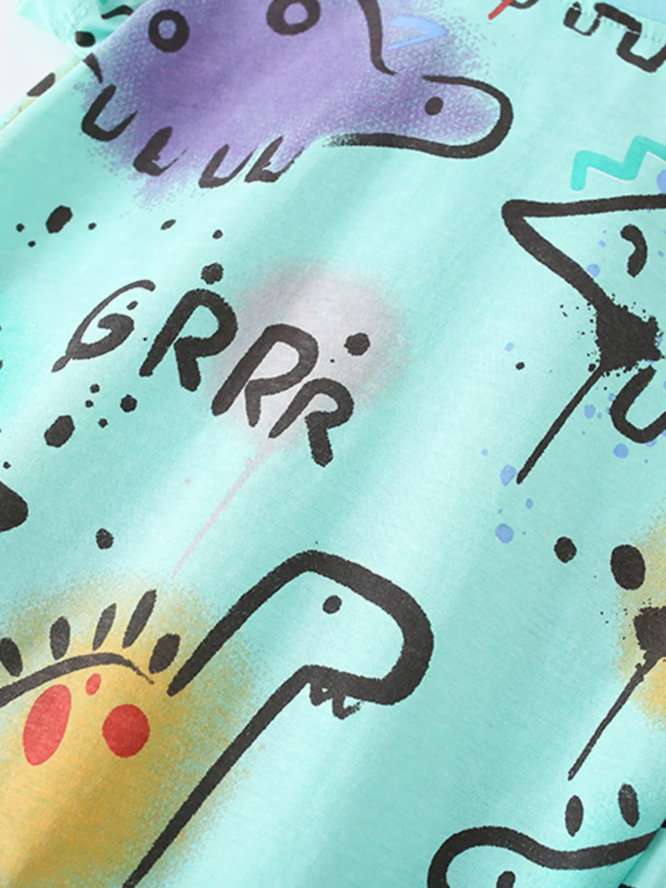 Close-up of dinosaur print lettering and purple dinosaur detail on multicolor children's t-shirt