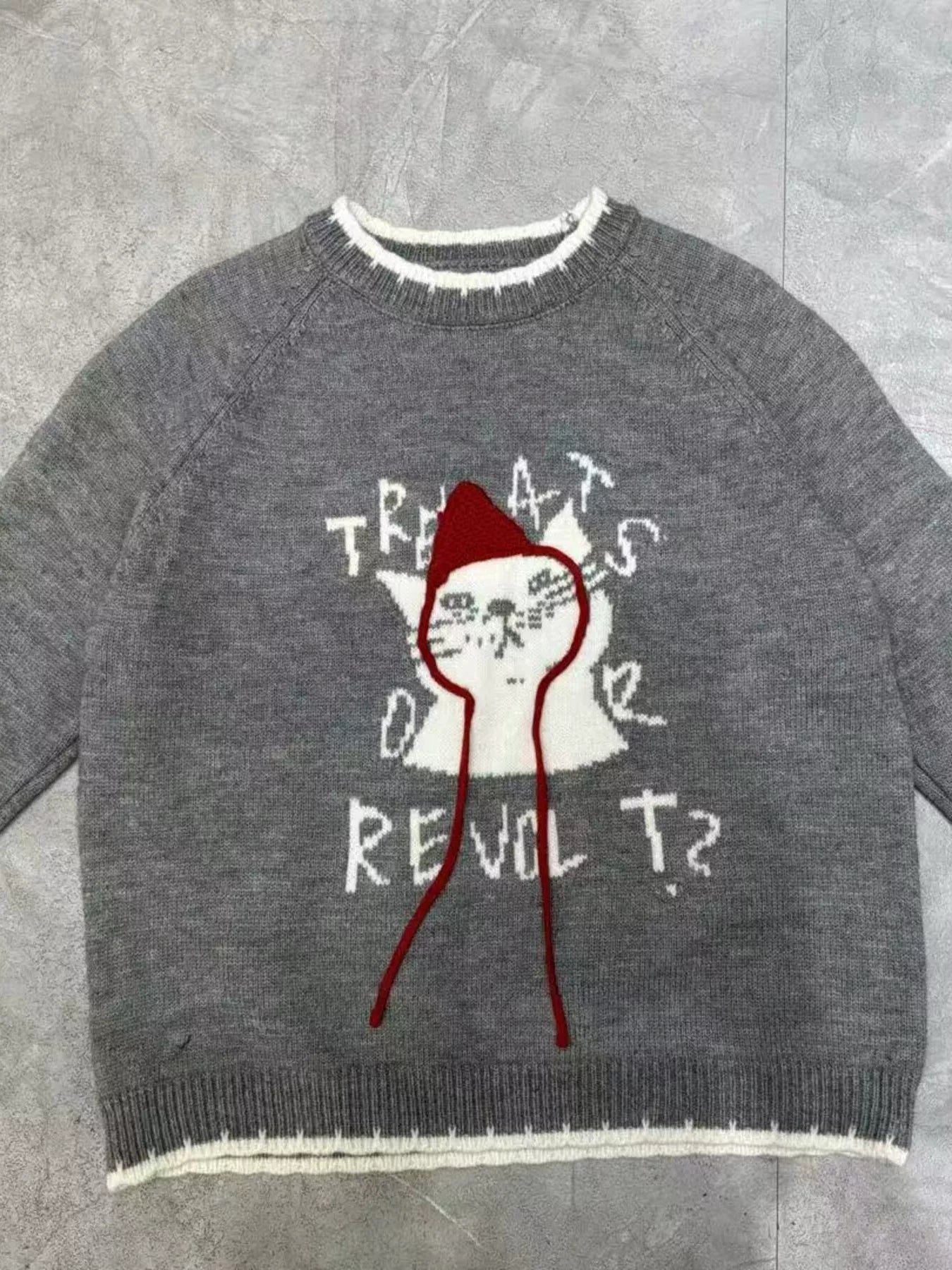 Flat lay of gray cat sweater with white cat and red strings
