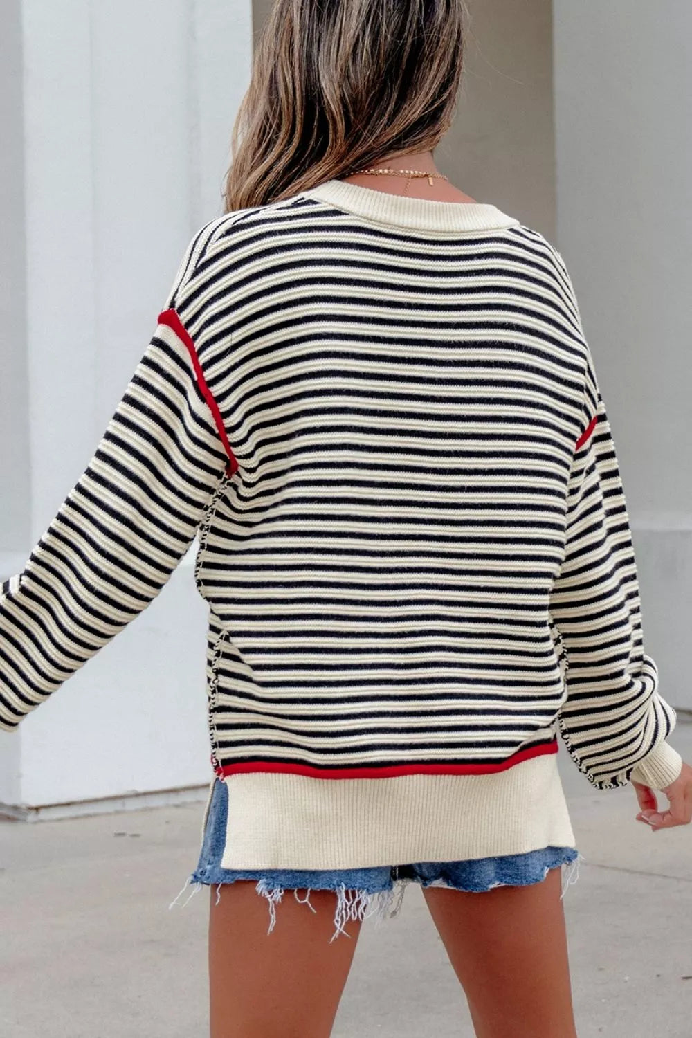 On-model back view of the black and cream striped oversized sweater with red accents