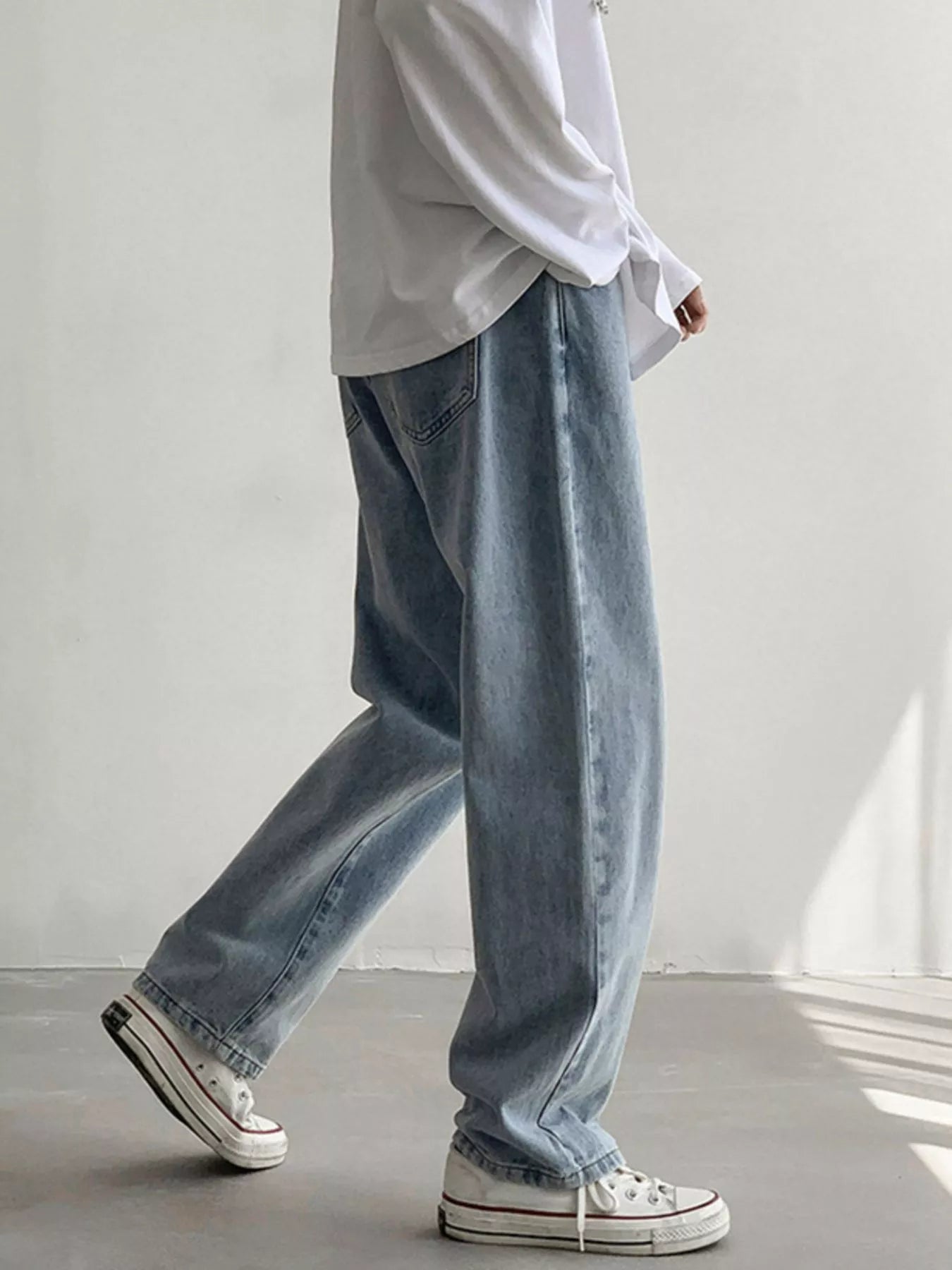 Men's Air Force Blue loose fit wash jeans on model, side view while walking.
