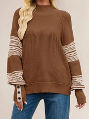 Front view of the brown waffle knit sweater with cream patterned sleeves and button cuffs, arms relaxed.