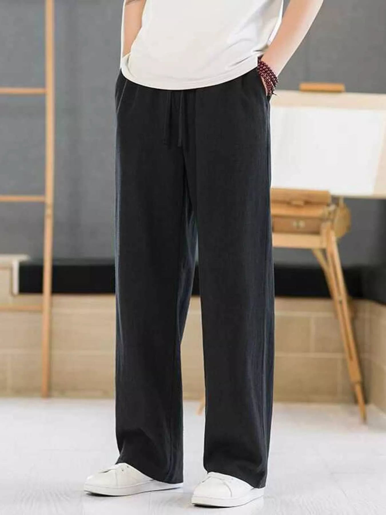 Men's black casual pants with a drawstring waist and pockets.