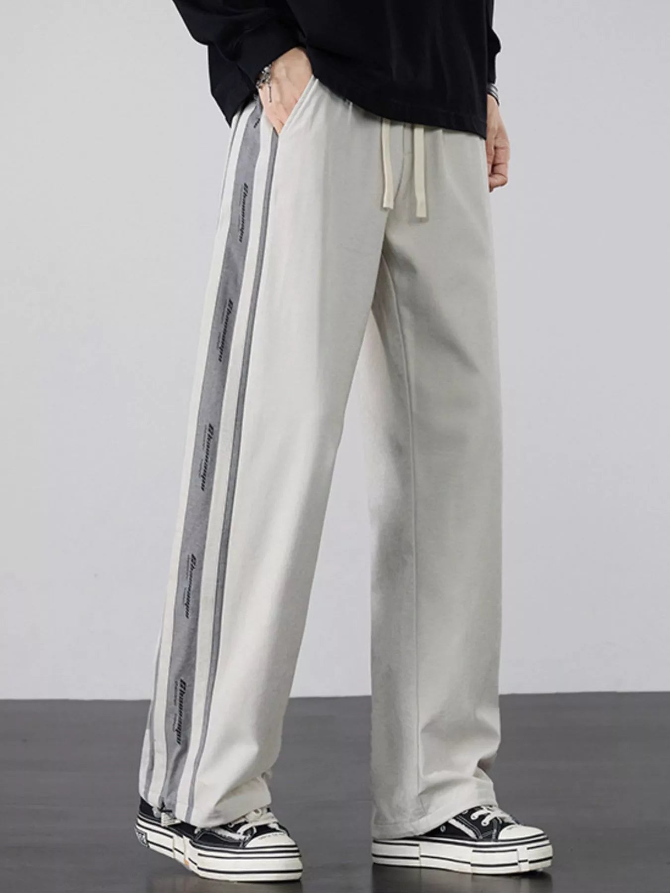Men's light gray loose-fit pants with side stripes and a drawstring waist.