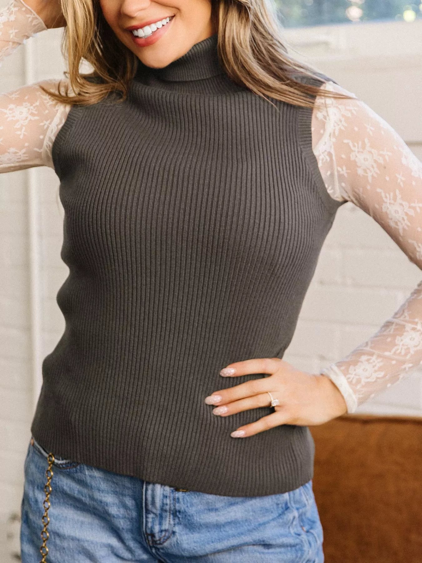 Front view of coffee brown ribbed high neck sweater vest with hand on hip