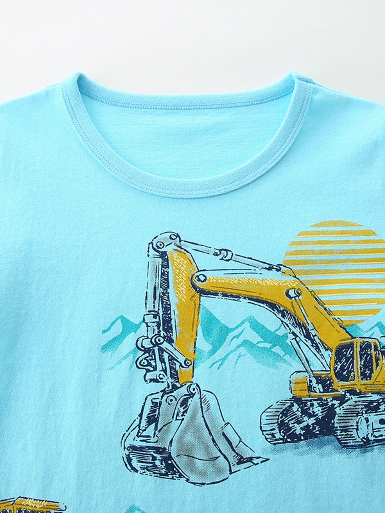 Close view of the round neckline and upper yellow excavator print on the pastel blue T-shirt