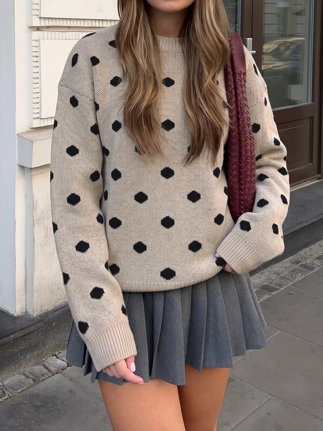 Front view of khaki polka dot dropped shoulder sweater with grey pleated skirt
