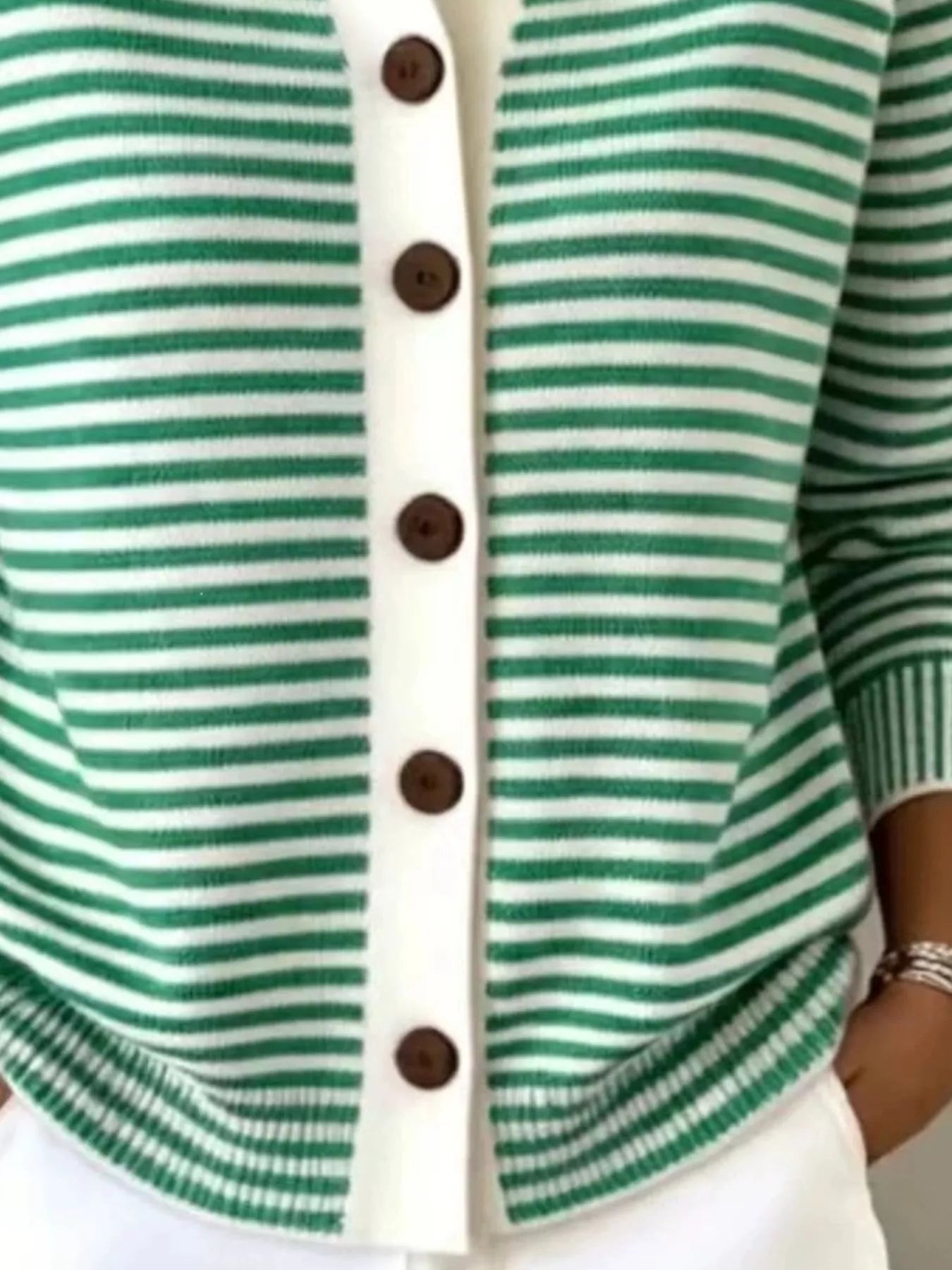 Close-up of the lower front and ribbed hem of a green and white striped knit cardigan
