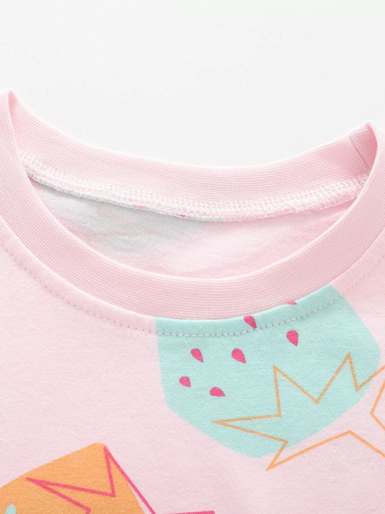 Close-up of pink children's tee neckline and mint strawberry print at chest