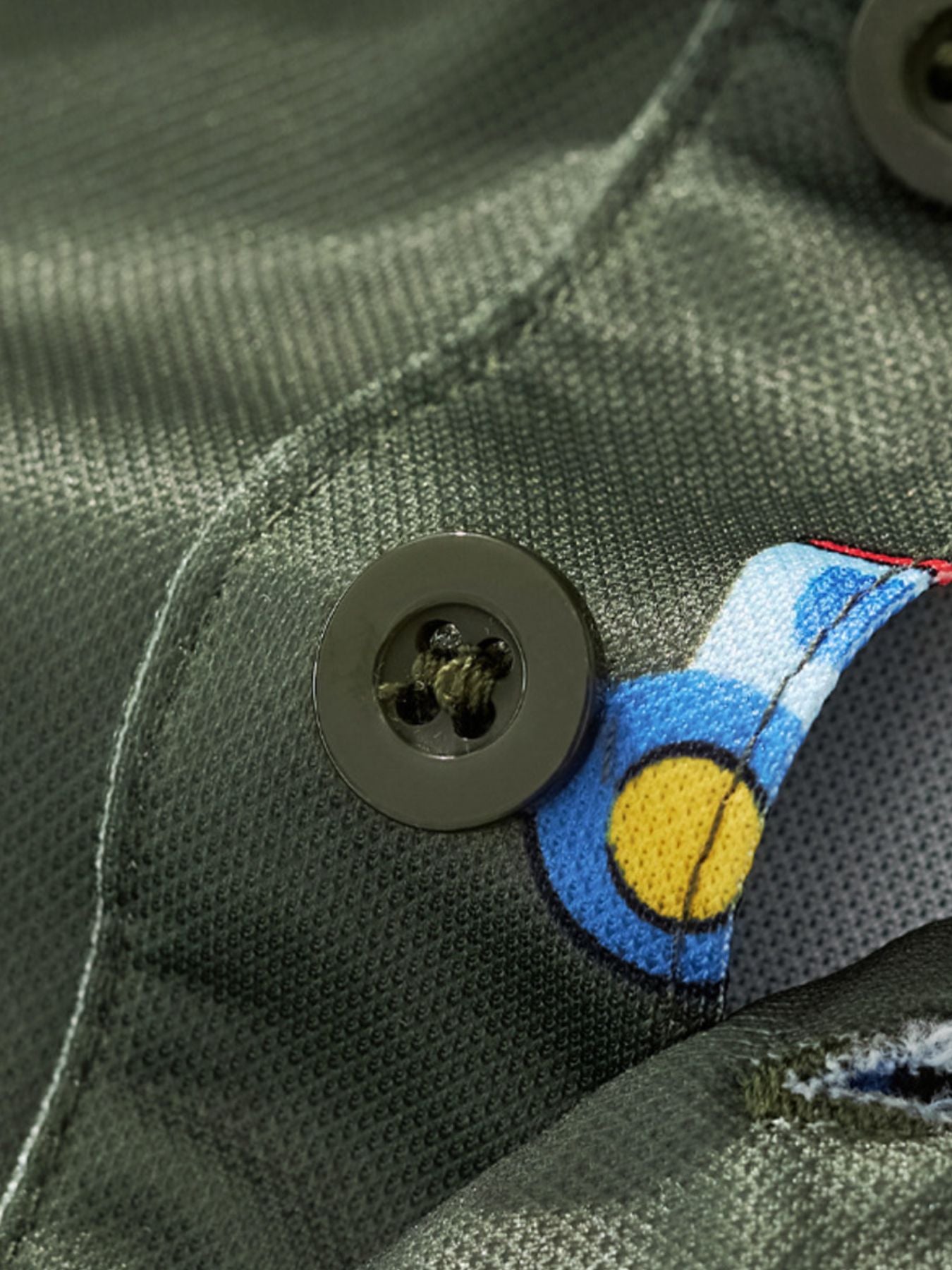 Close-up detail of the polo button and tractor print on army green children's shirt