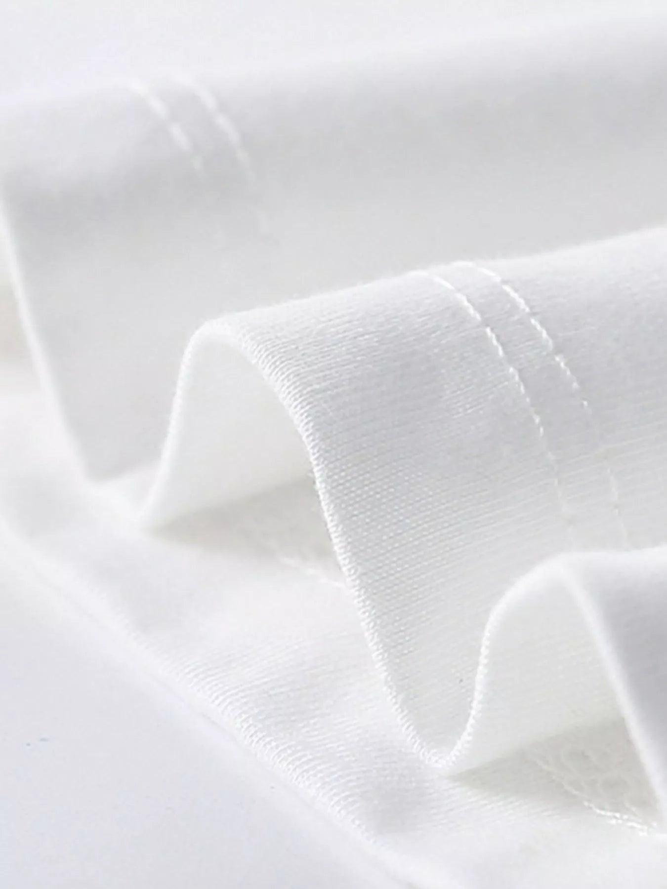 Close-up of white children's t-shirt sleeve hem stitching and smooth folded fabric