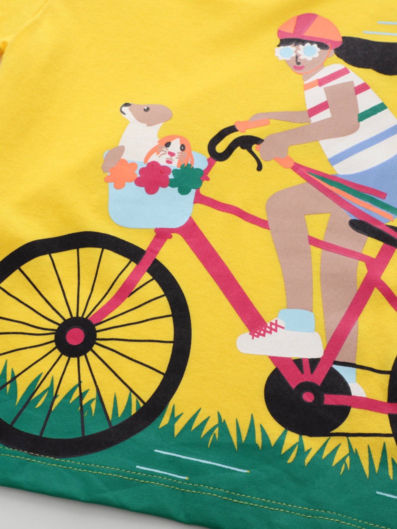 Close-up of bicycle basket with pets and flowers on yellow children's t-shirt