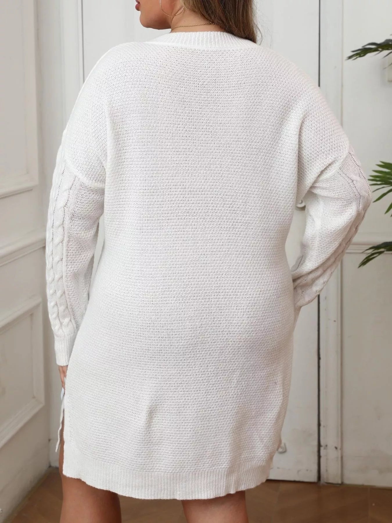Back view of white cable knit sweater dress with long sleeves and ribbed hem