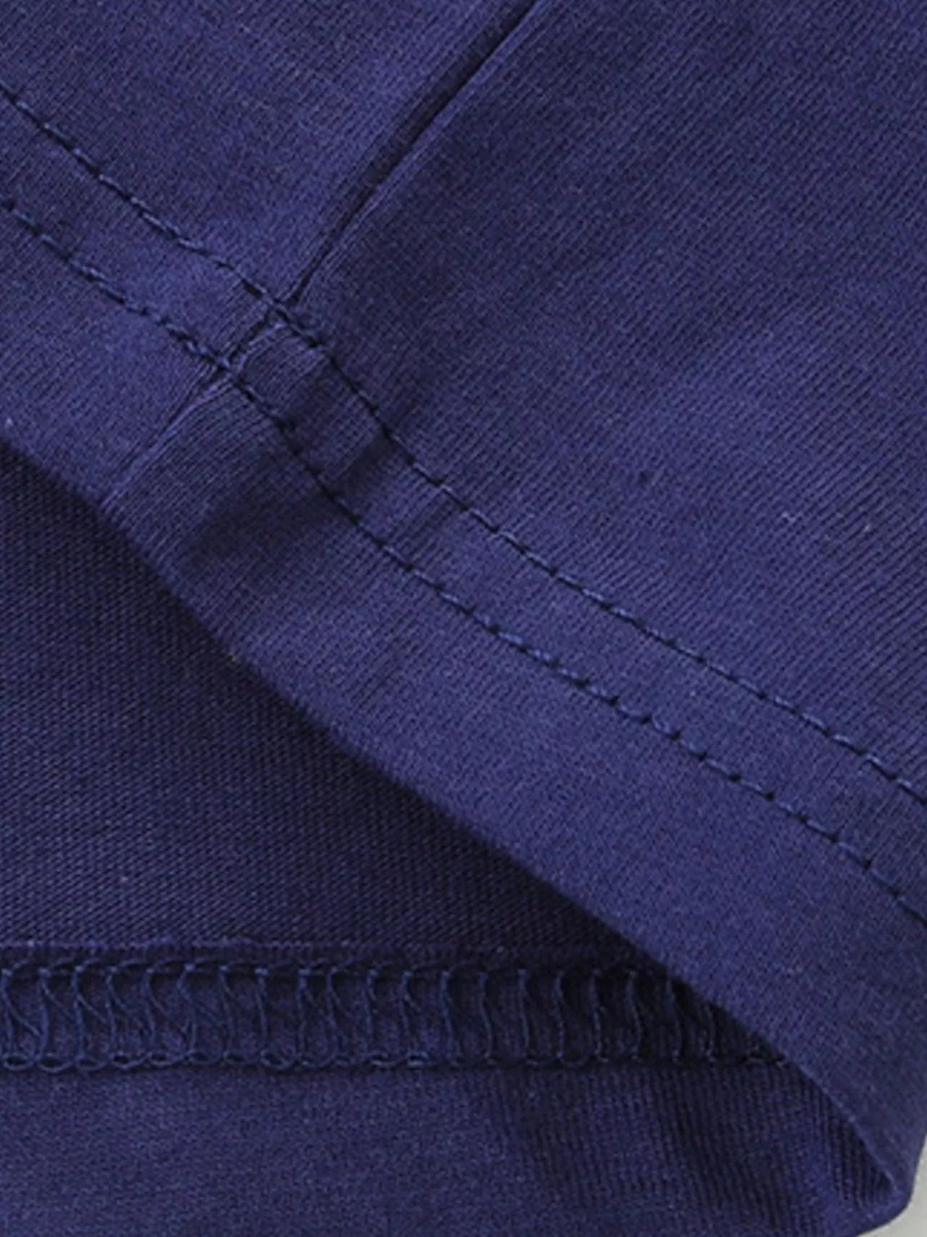Close up of dark navy stitching at a sleeve and hem seam on a children's tee