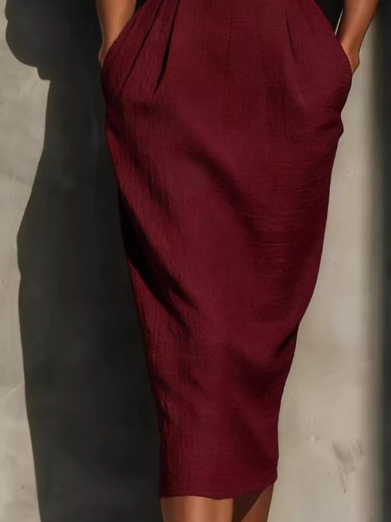Close view of burgundy puff sleeve midi dress skirt with pleats and waistband