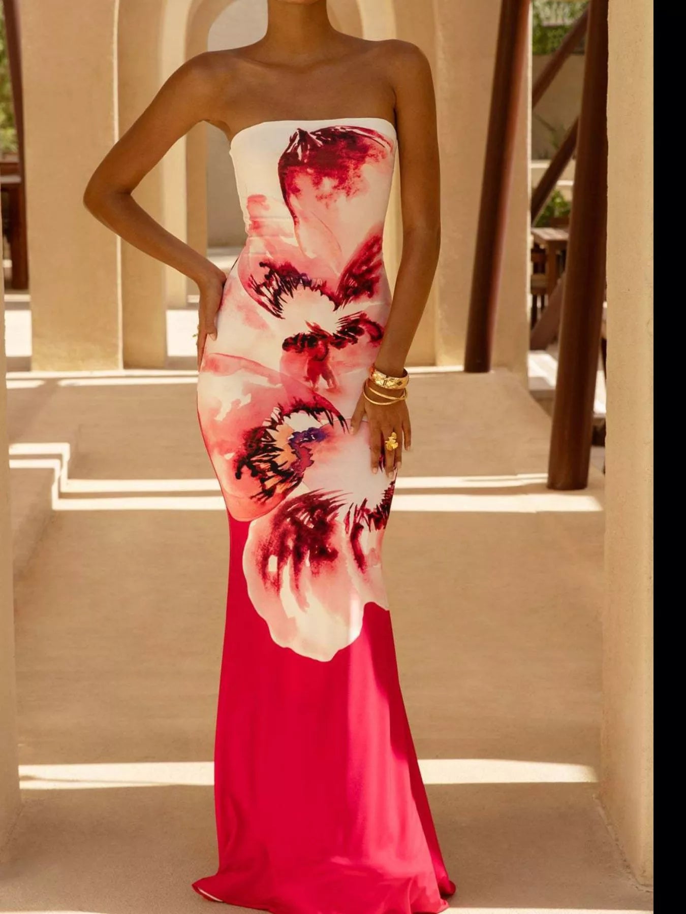 Model wearing strapless white and red floral tube maxi dress, front view with hand on hip