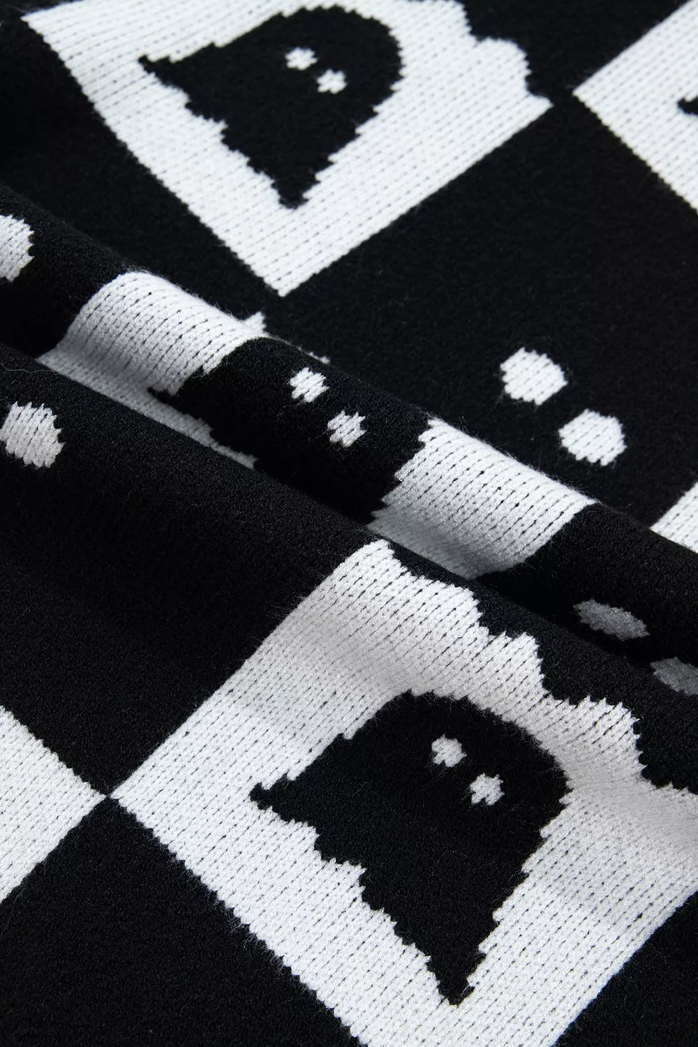 Close up of black and white ghost checkerboard knit fabric in a fold