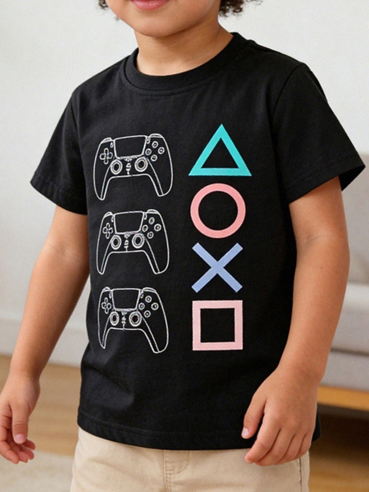 Black children's round neck T-shirt with white game controller outlines and colorful geometric shapes, front view