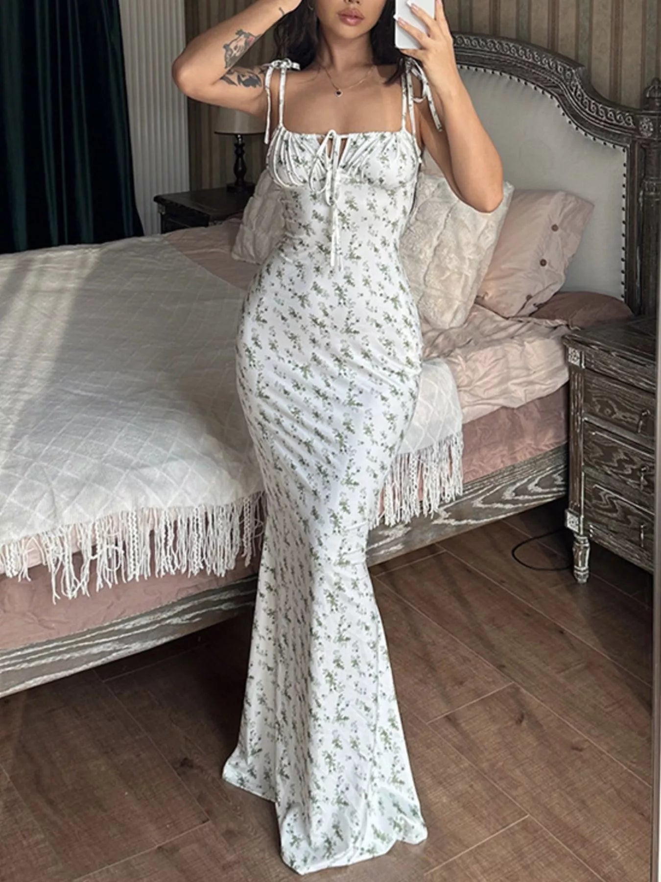 Model taking mirror selfie in white floral print bodycon maxi dress with tie straps and ruched bodice