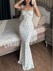 Model taking mirror selfie in white floral print bodycon maxi dress with tie straps and ruched bodice