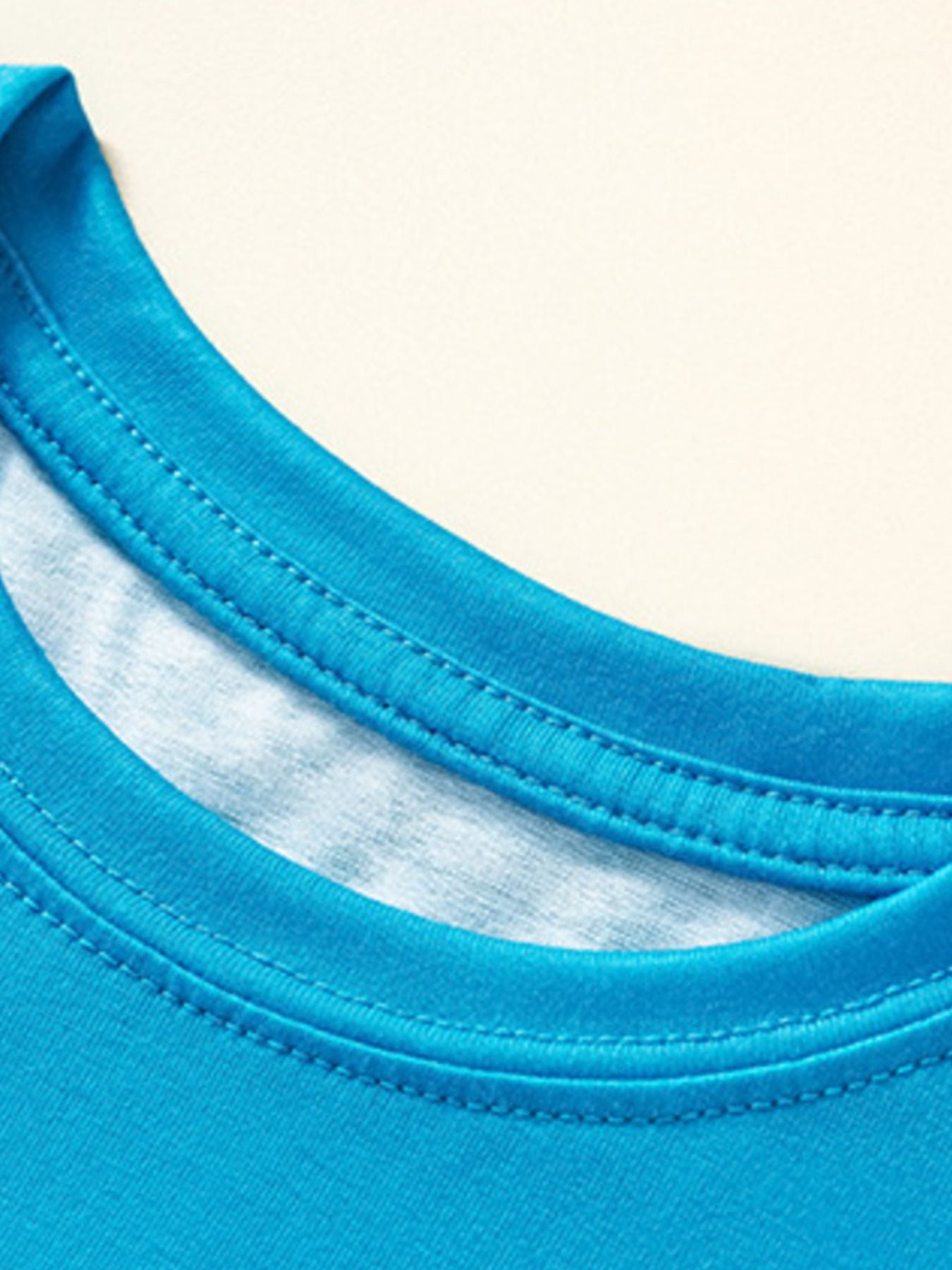 Close-up of the stitched round neckline on the sky blue children's shark tee