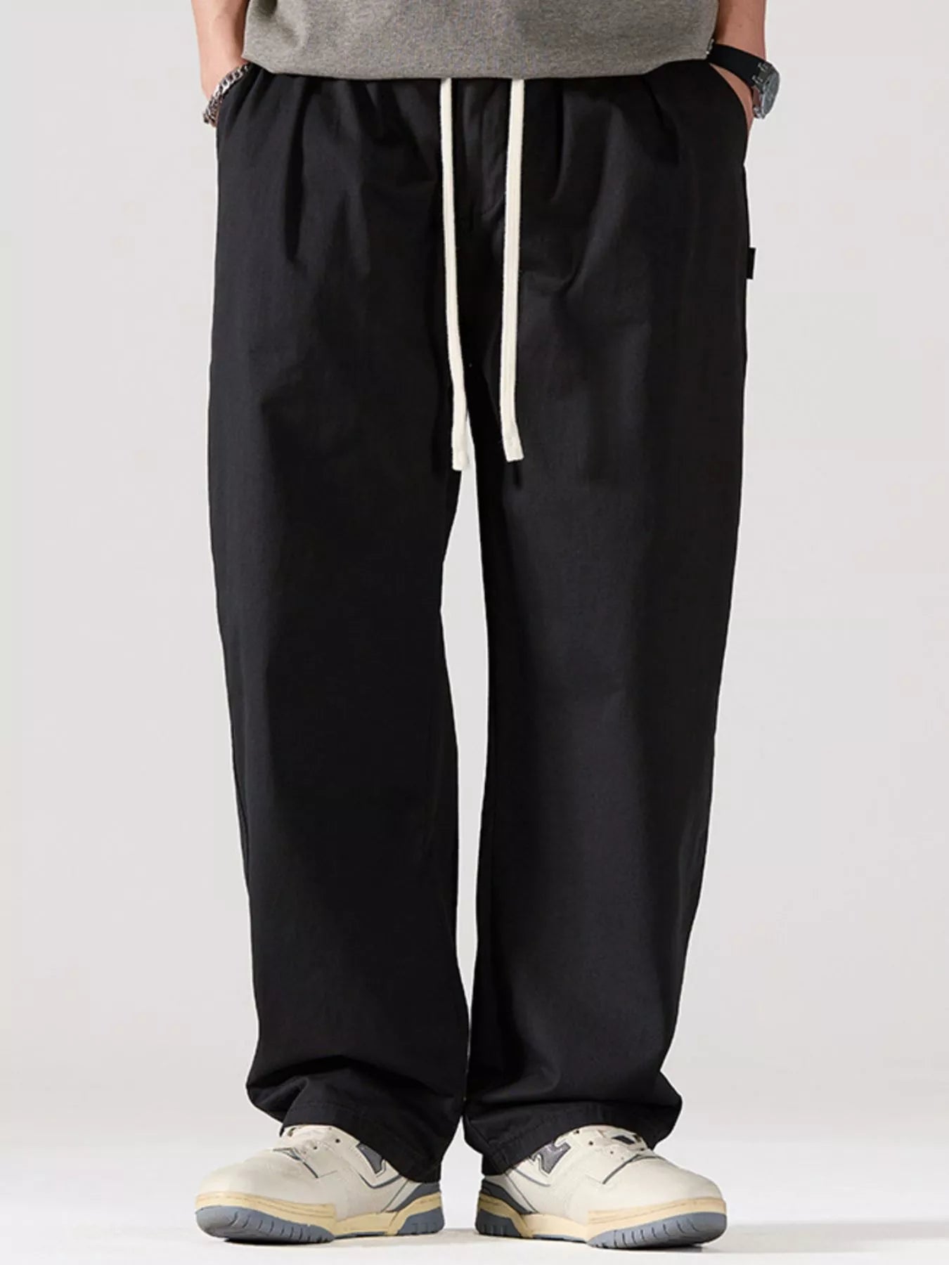 Men's black oversized casual pants with a drawstring waist and pockets.